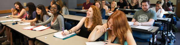 students laughing in a class while taking notes